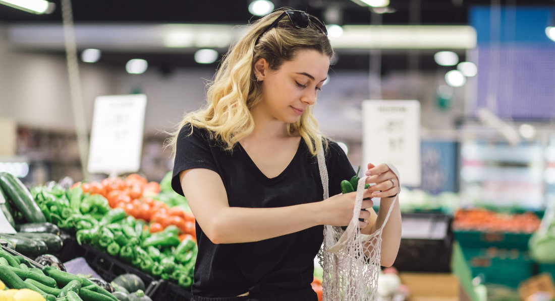 Eine Frau kauft im Supermarkt unverpacktes Gemüse ein