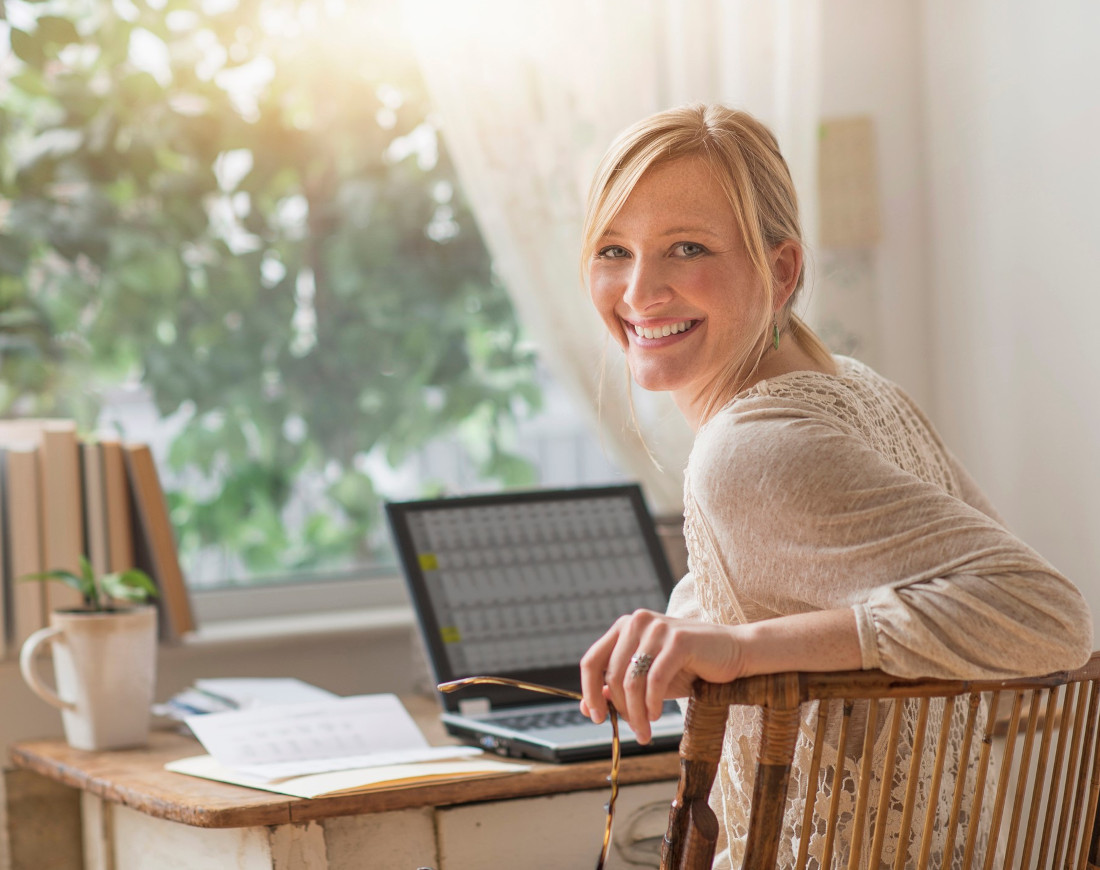 Junge Frau mit Laptop freut sich über mehr netto vom brutto