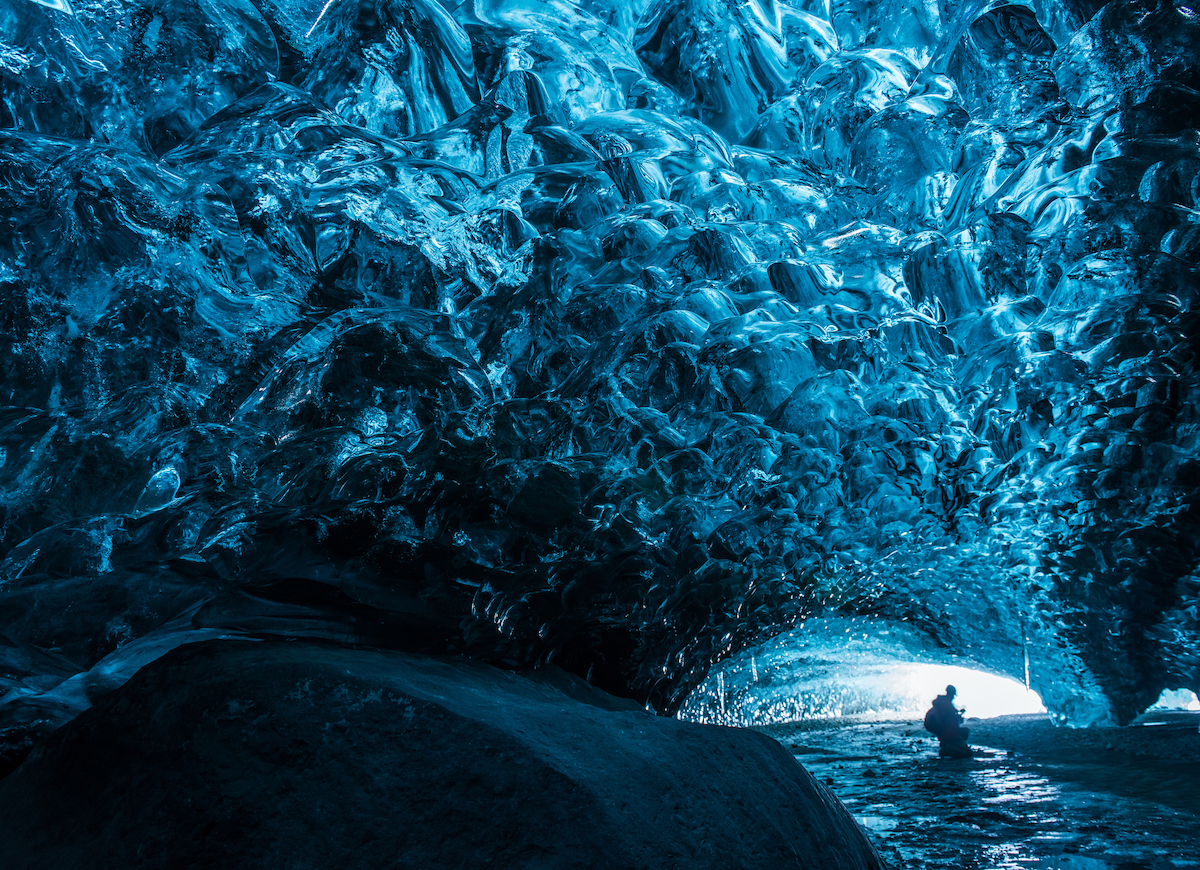 Besucher in der Vatnajökull-Höhle auf Island, über ihm Gletscher in leuchtendem Türkis