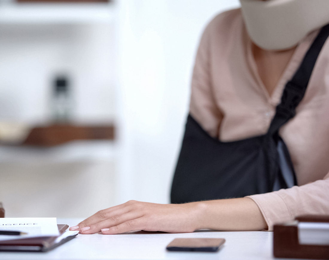 Frau mit Halskrause und Armbinde sitzt vor medizinischen Unterlagen