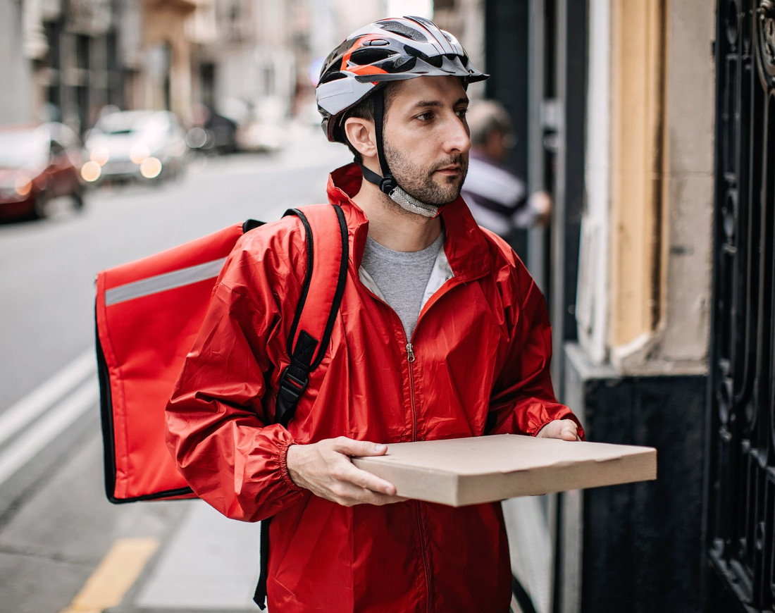 Ein Mann liefert eine Pizza an die Haustür