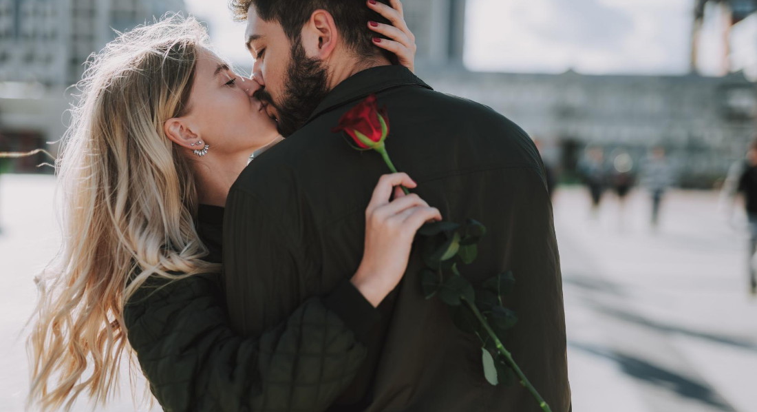 Eine Frau erhält vom Mann eine Rose zum Valentinstag und küsst ihn