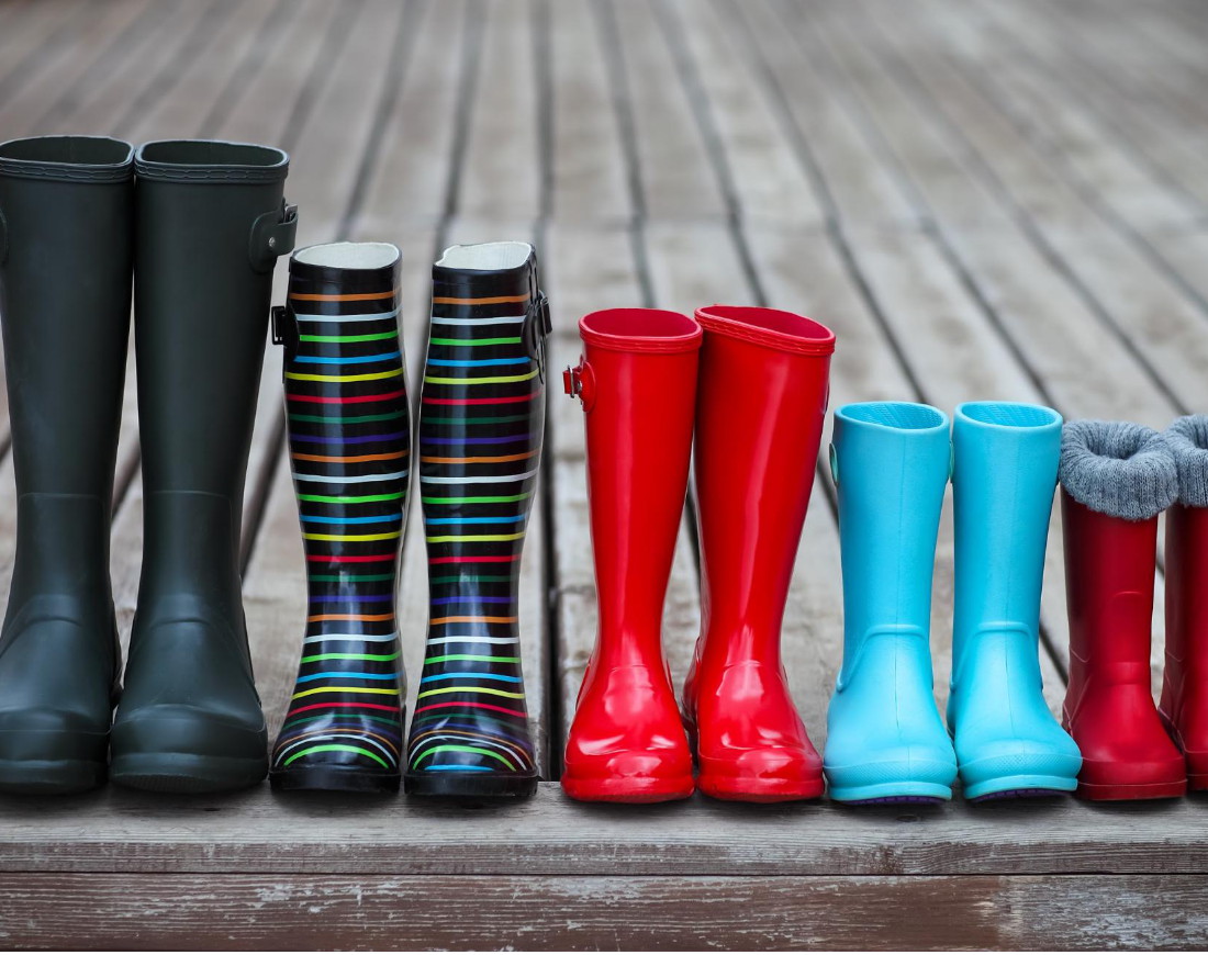 Fünf Paar Regenstiefel stehen nebeneinander, von links nach rechts werden sie kleiner