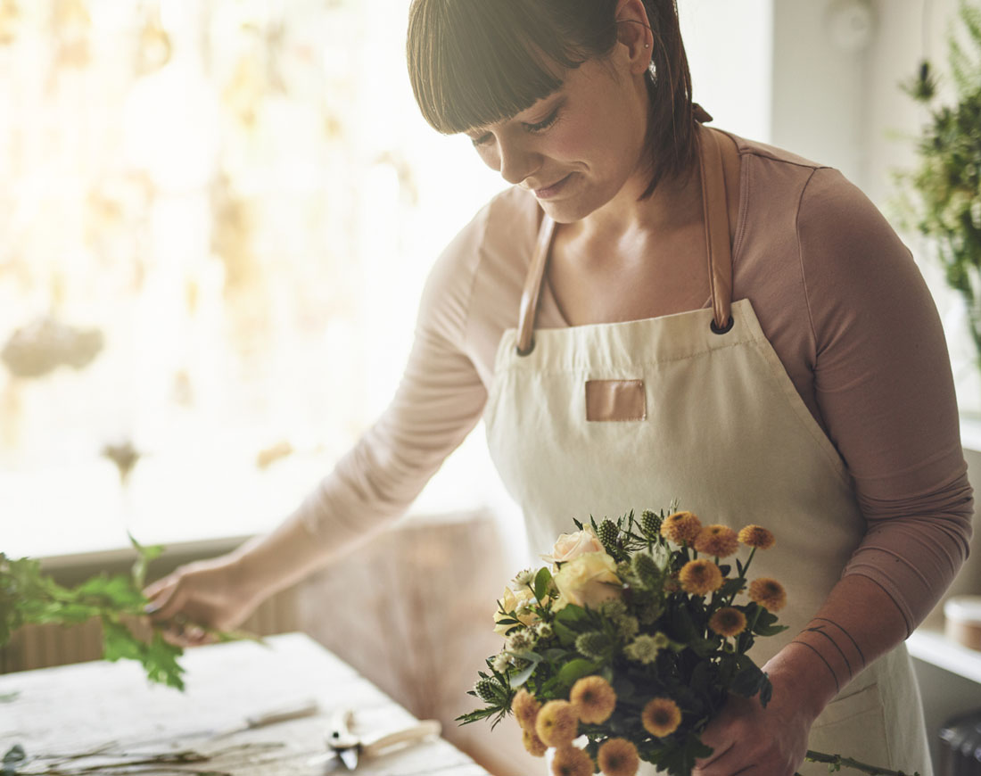 Eine junge Frau steht an einem Tisch und bindet Blumen zu einem Strauß
