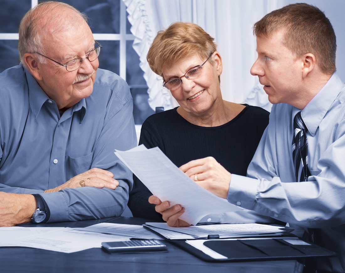 Ein Bankberater erklärt einem älteren Ehepaar die Berechnung der Zinsen seines Sparbriefes