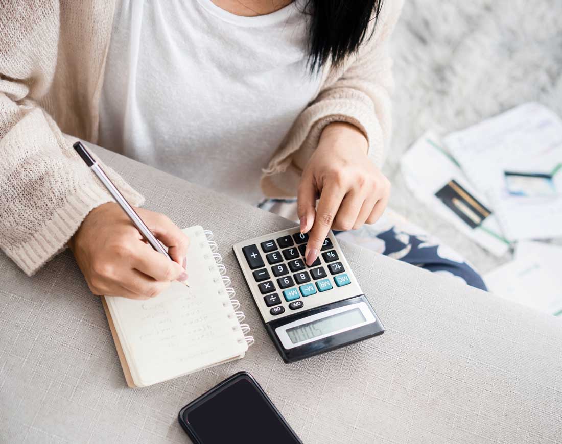 Eine Frau rechnet ihre Schulden mit einem Taschenrechner aus