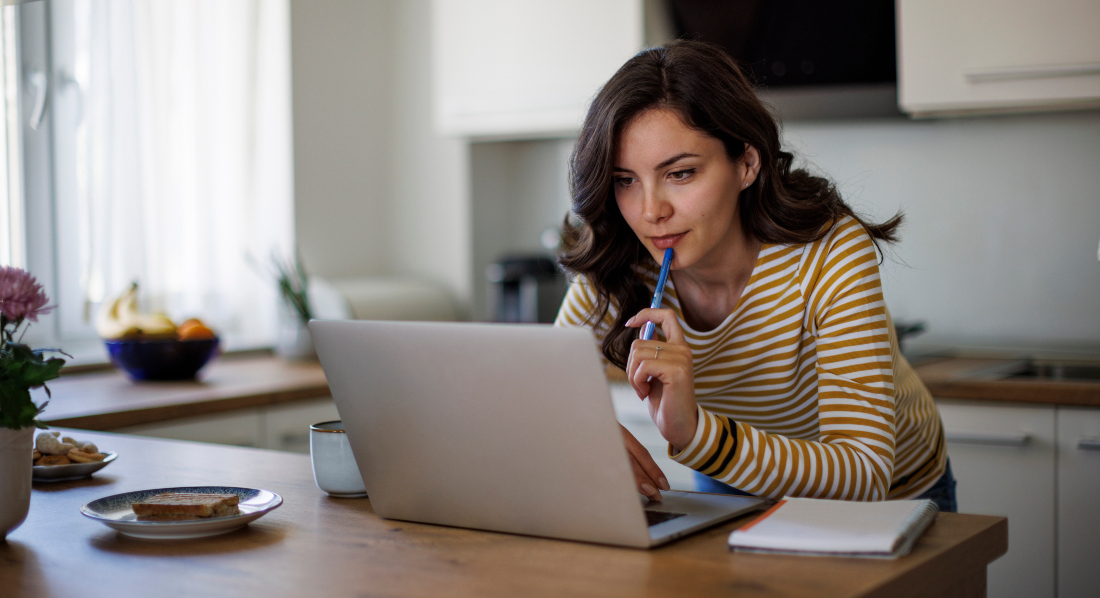 Eine Frau schaut in einer Küche auf ihren Laptop