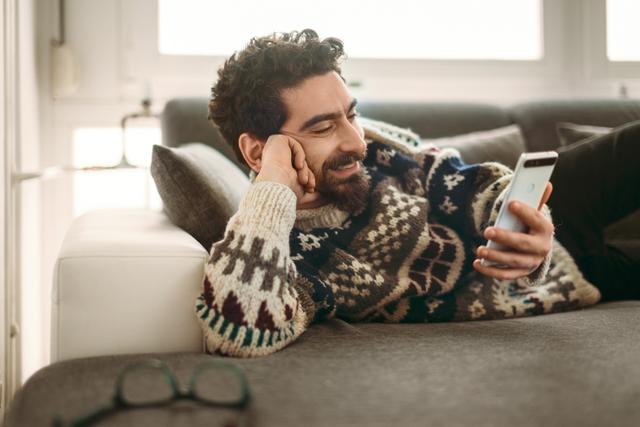 Ein Mann macht die Online-Identifikation der Digitalen Antragsstrecken der Hanseatic Bank von der Couch aus, weil es so einfach ist