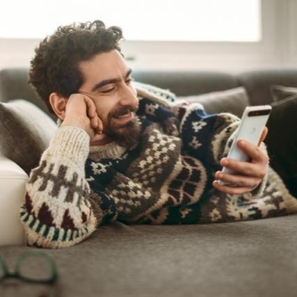 Ein Mann macht die Online-Identifikation der Digitalen Antragsstrecken der Hanseatic Bank von der Couch aus, weil es so einfach ist