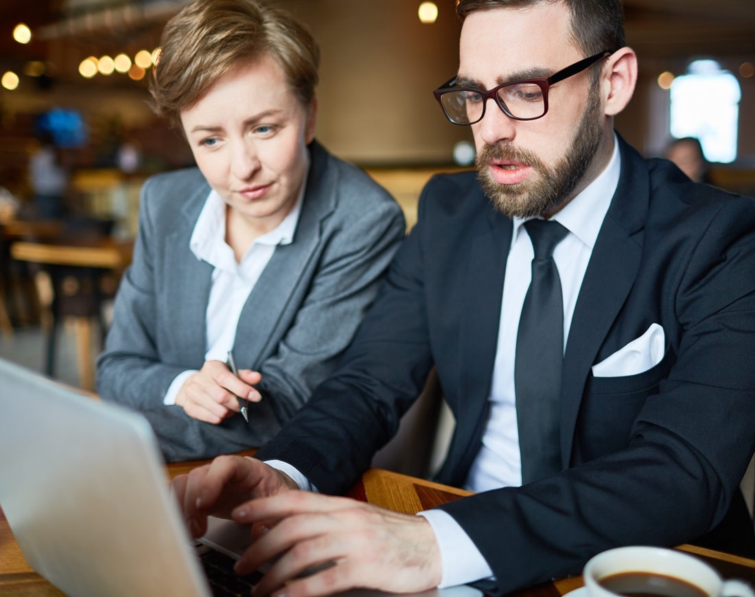 Arbeitgeber und Arbeitnehmerin sitzen gemeinsam vor einem Laptop und vereinbaren die Entgeltumwandlung für die betriebliche Altersvorsorge