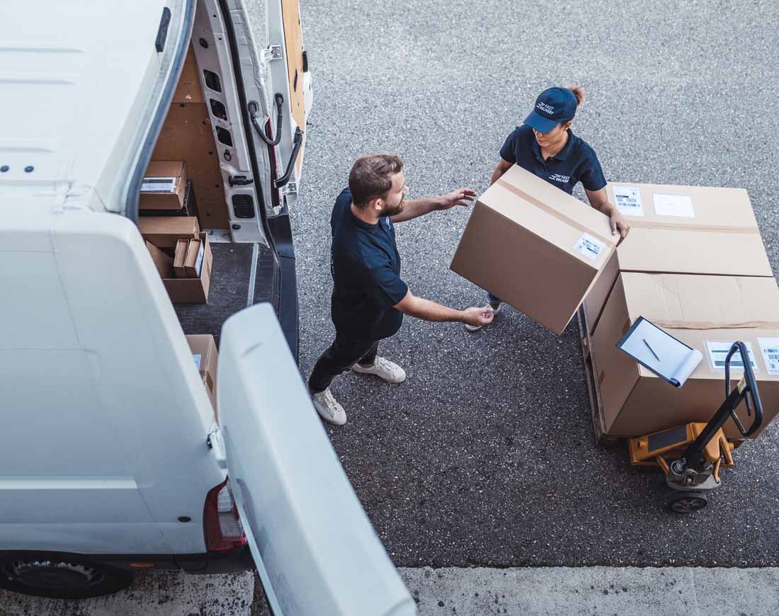 Eine Frau und ein Mann von einem Lieferdienst laden Pakete in einen Lastwagen