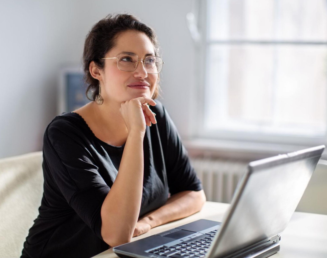 Frau sitzt nachdenklich am Laptop