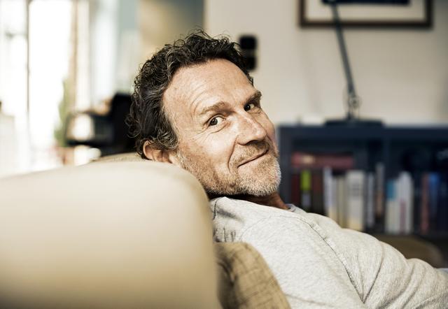 Alfred Schmid relaxt auf der Couch, weil er mit dem Sparbrief der Hanseatic Bank eine gute Festgeldanlage hat um etwas für seine Enkelin zu sparen