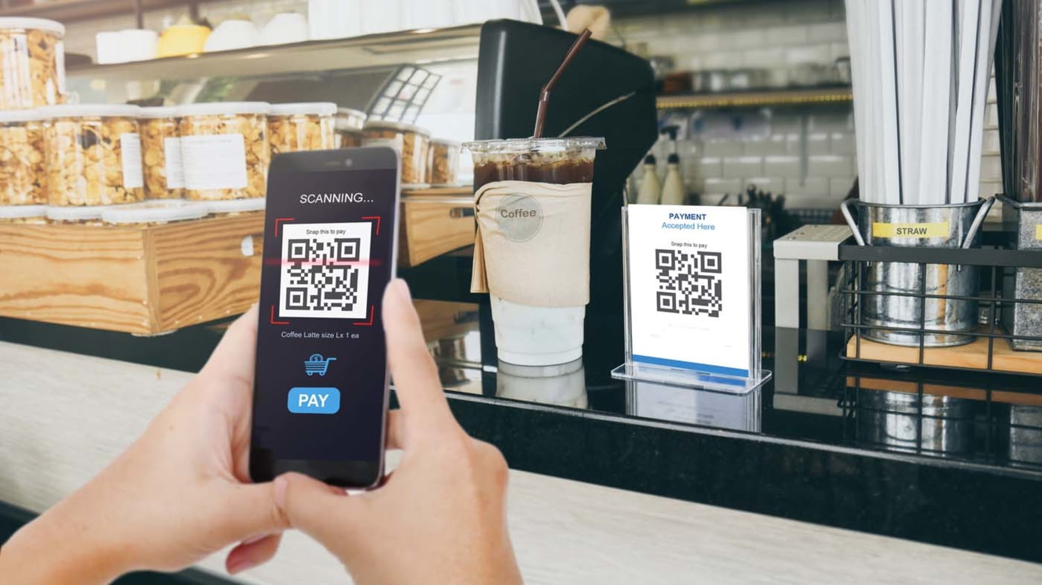 Ein Smartphone scannt in einem Café den QR-Code an der Kasse ein
