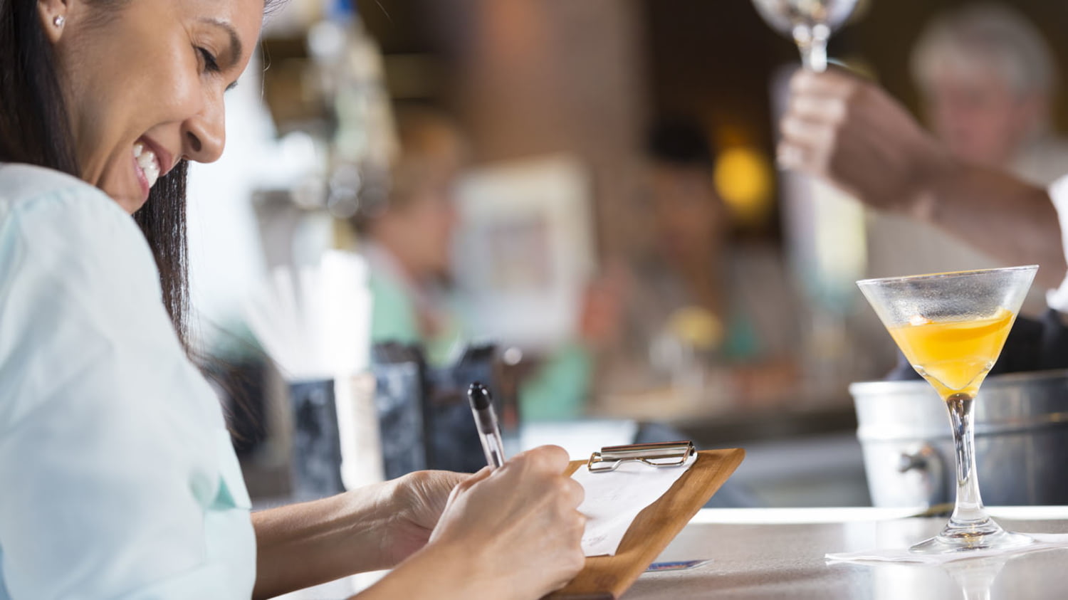 Eine junge Frau sitzt im Restaurant und unterschreibt ihre Rechnung für die Kreditkartenzahlung