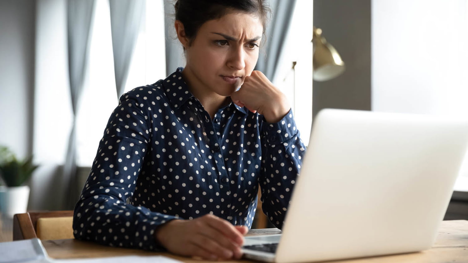 Junge Frau arbeitet mit kritischem Blick am Laptop