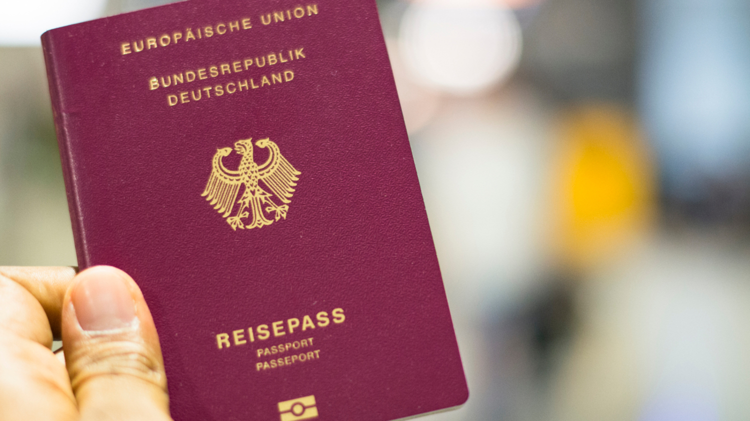 Eine junge Frau sitzt mit ihrem Gepäck niedergeschlagen in einer Wartehalle im Flughafen