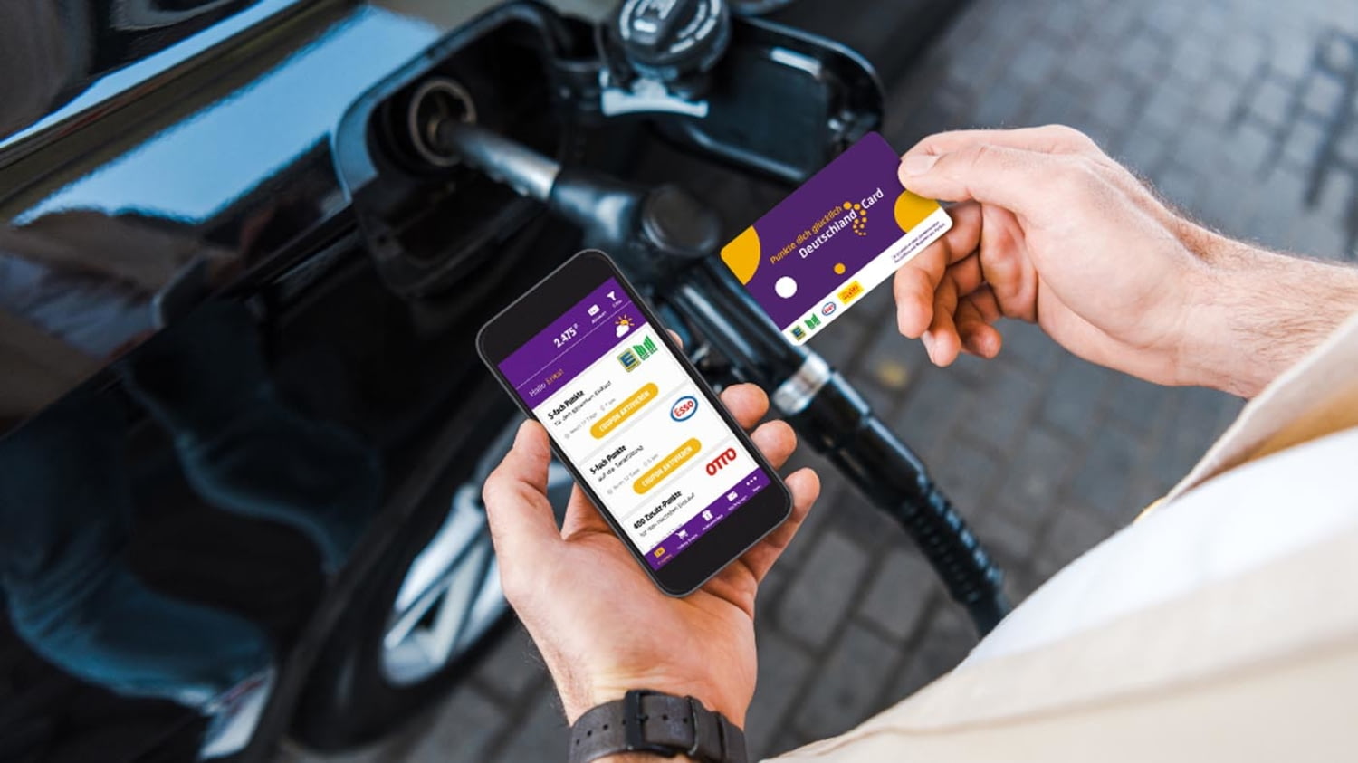 Beim Tanken hält ein Mann sowohl ein Smartphone mit der DeutschlandCard-App als auch die Karte in den Händen