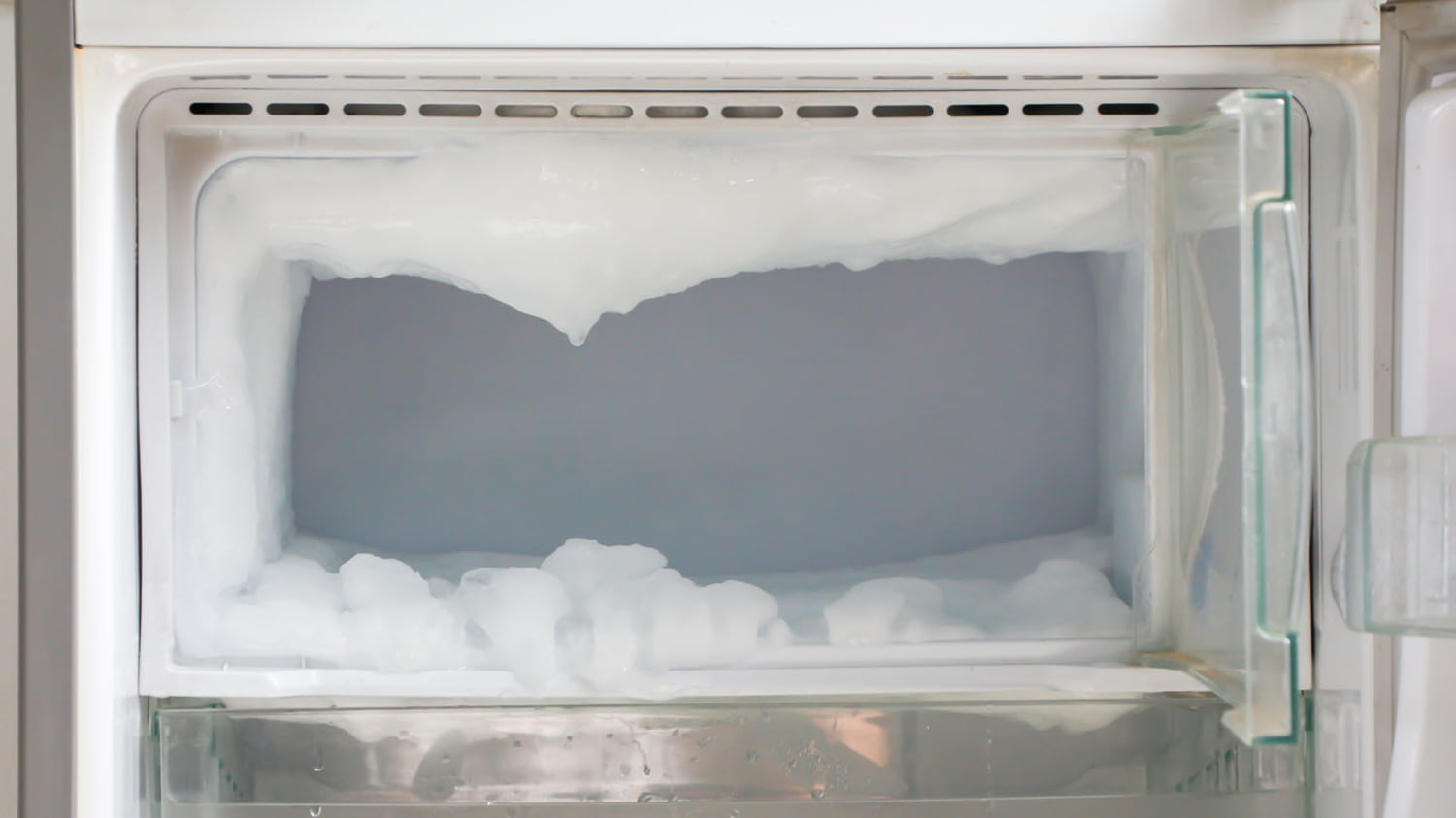 Geöffnetes Fach eines Tiefkühlgeräts mit zentimeterdicker Eisschicht