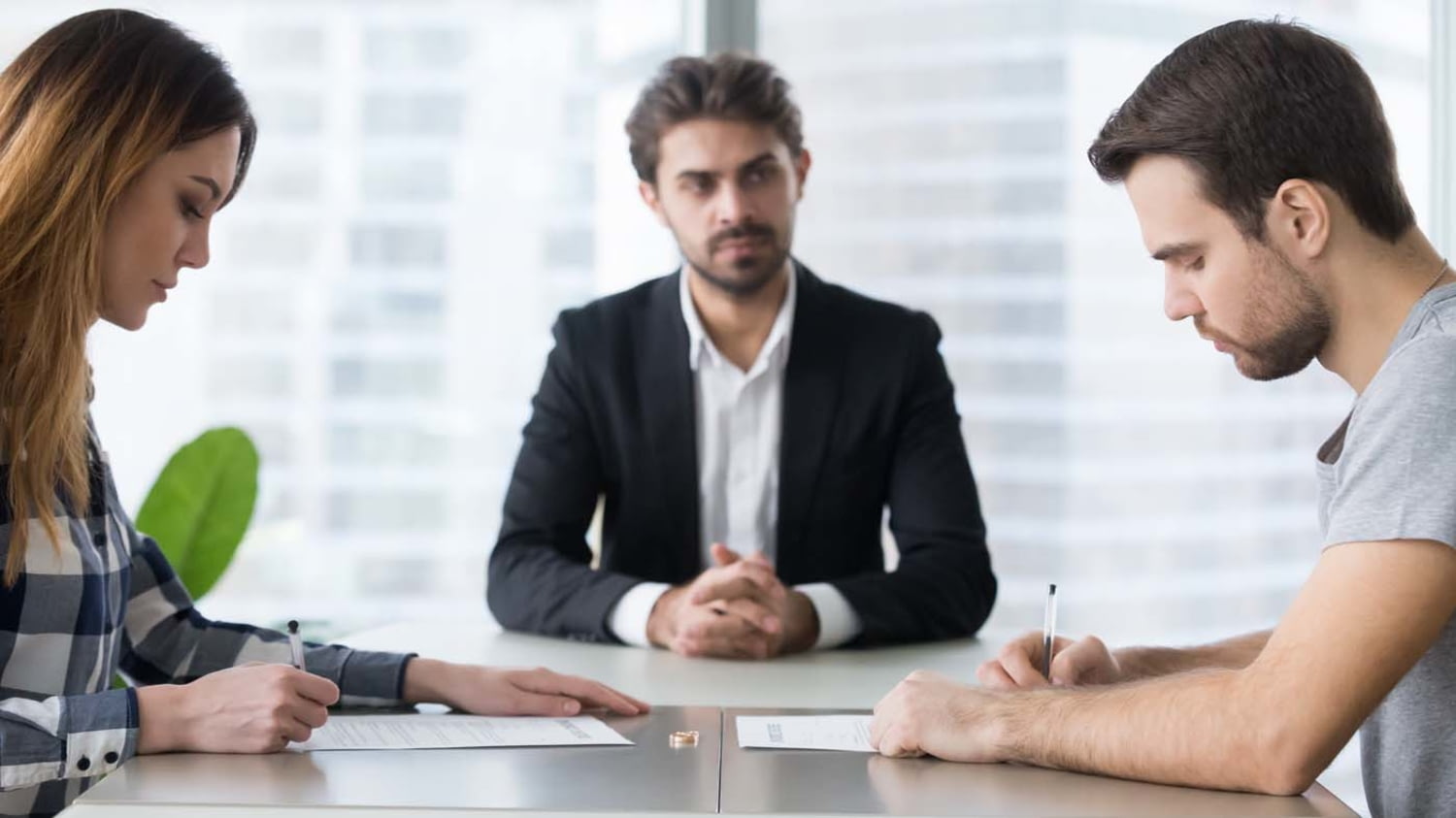 Paar unterschreibt am Schreibtisch eines Anwalts einen Vertrag