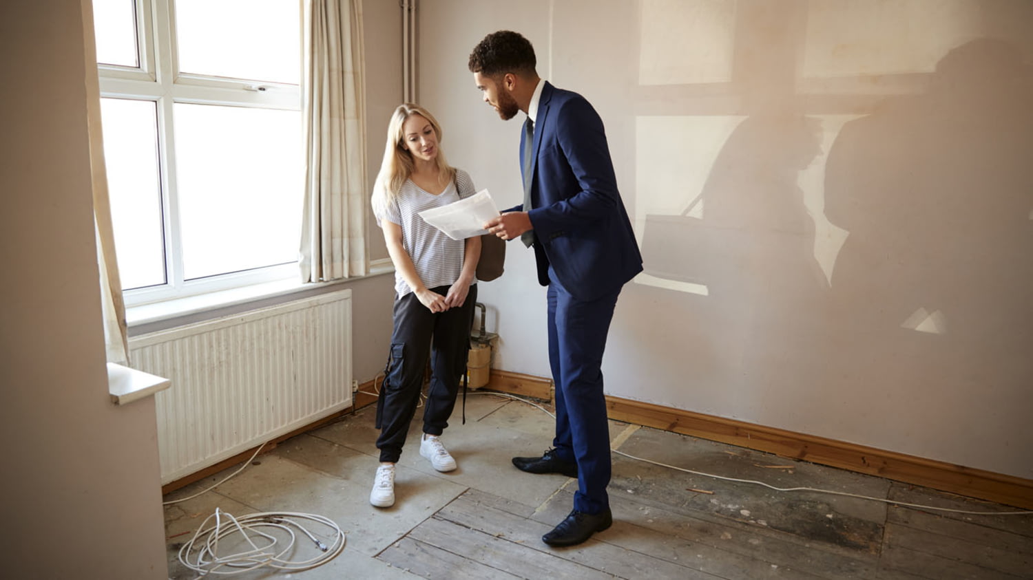 Ein Makler zeigt der Bewerberin um eine Wohnung ein Dokument