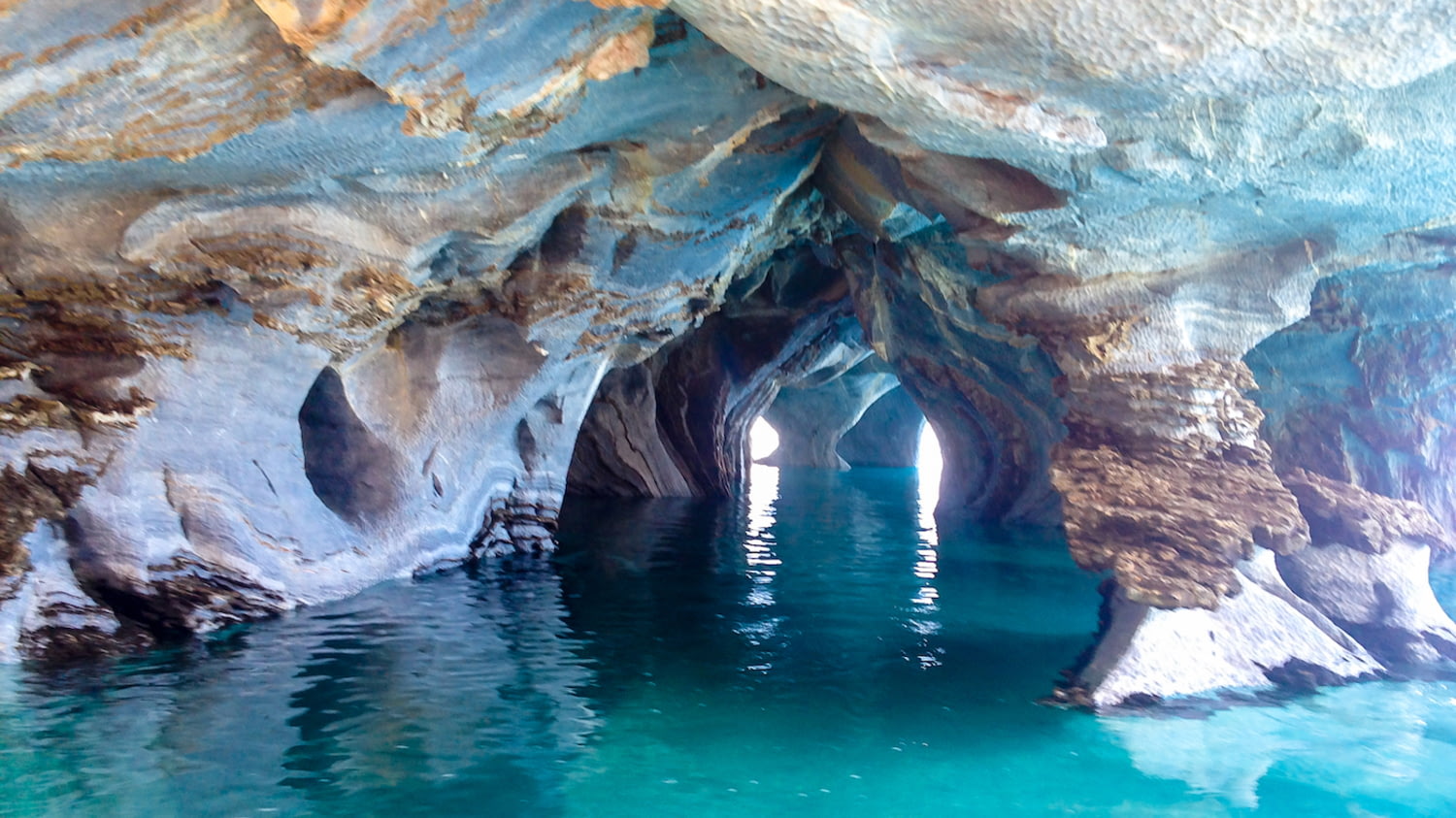 Höhlen aus farbigem Marmor über einem türkis schimmernden See