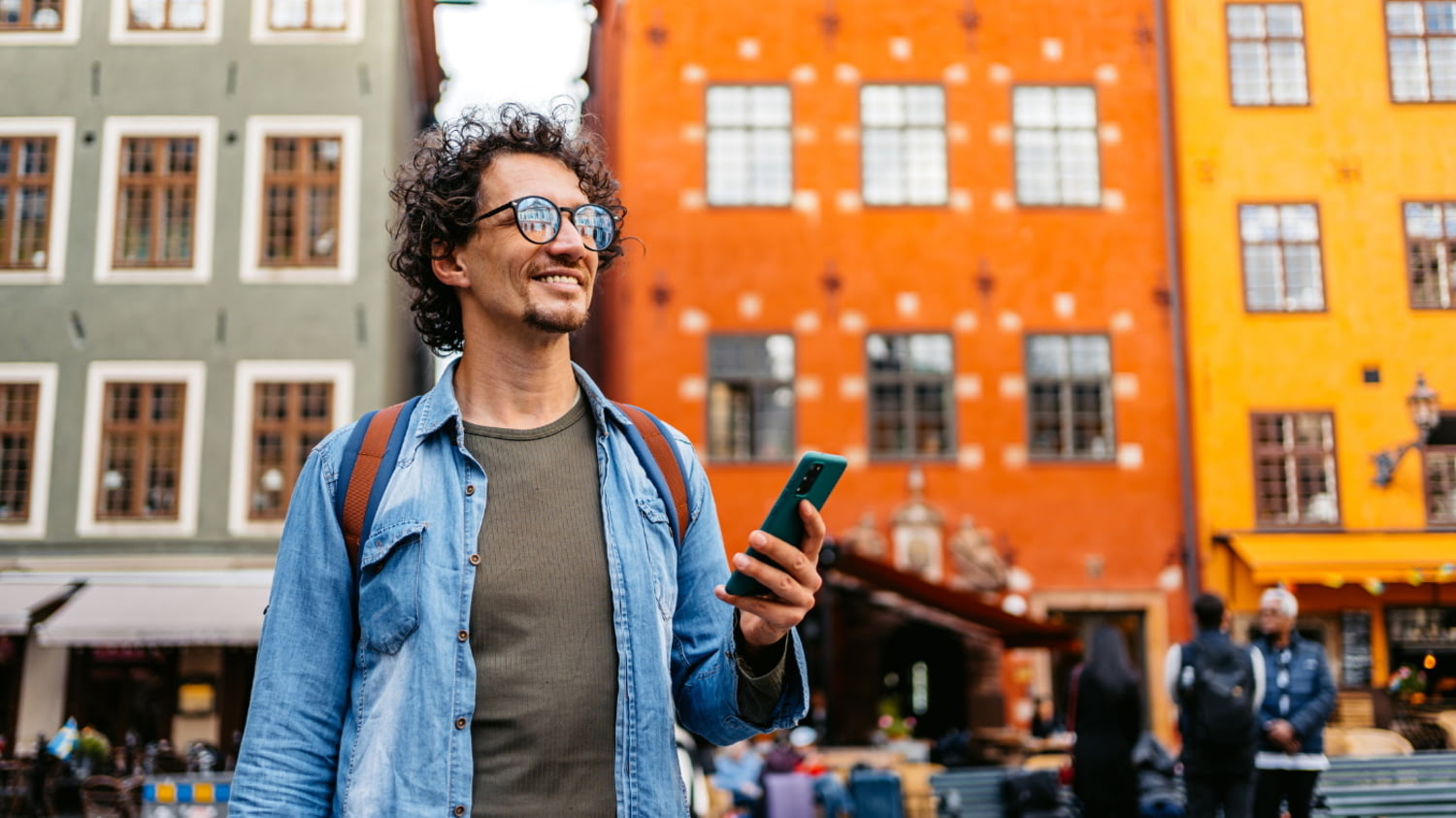 Ein junger Mann ist mit Smartphone und Rucksack in Stockholm unterwegs