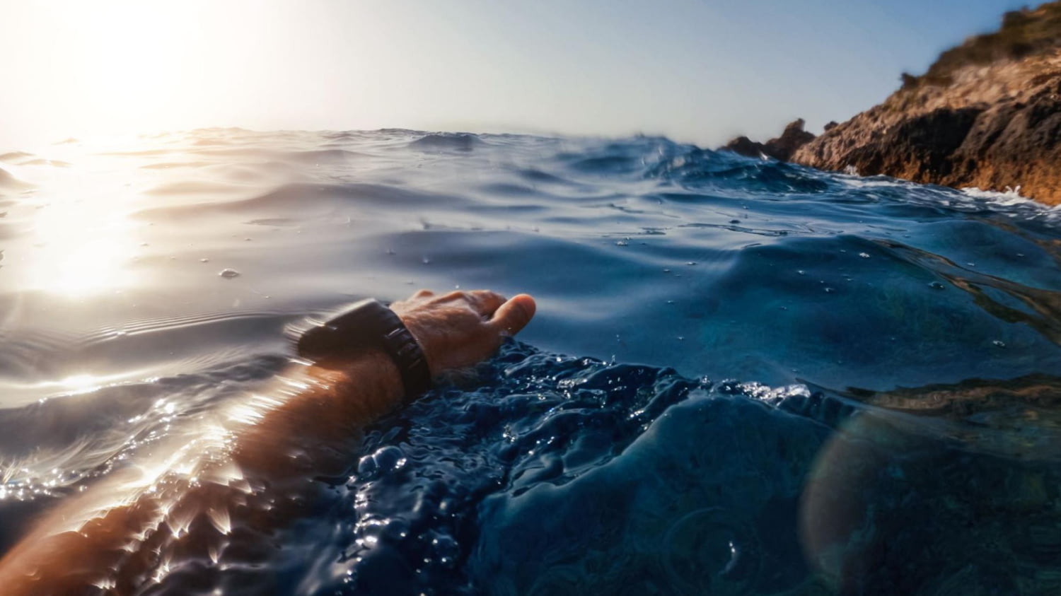 Mensch schwimmt mit Smartwatch im Meer