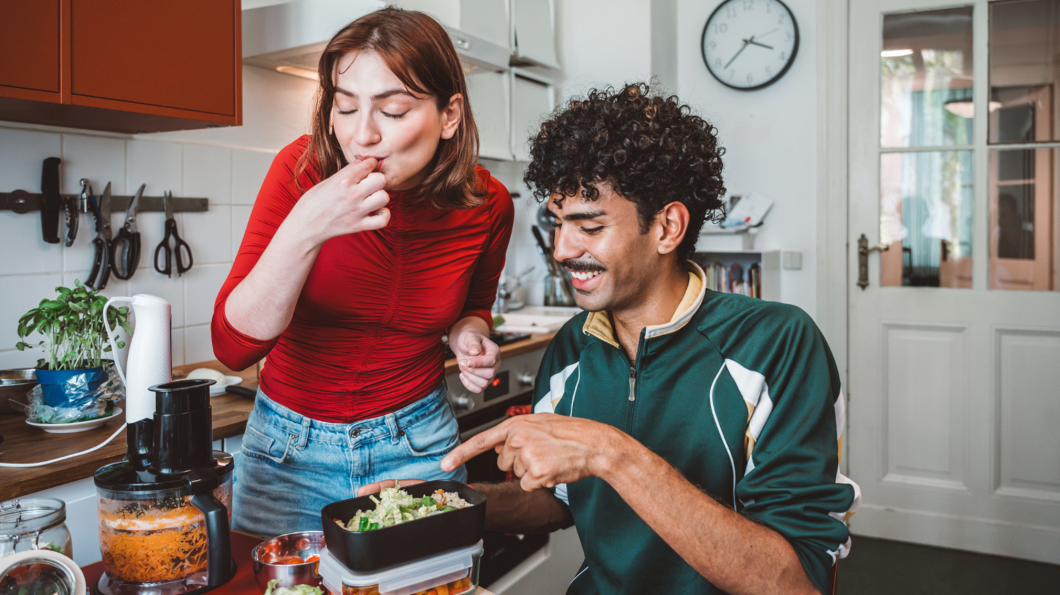 Ein junges Paar bereitet frisches Essen zu und f&uuml;llt es in Beh&auml;lter ab