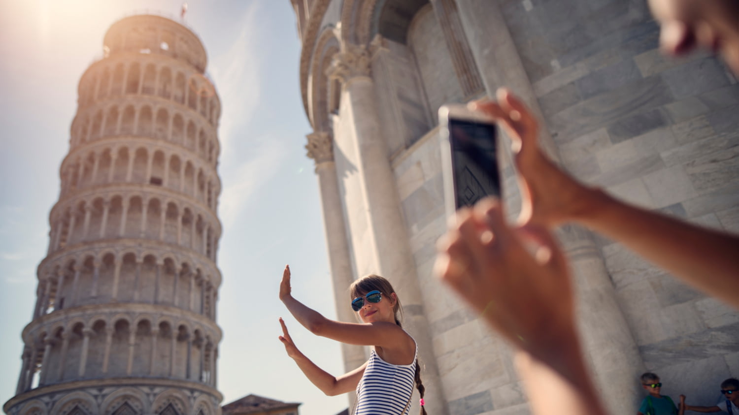 Eine Frau posiert vor dem schiefen Turm von Pisa und wird dabei mit Handy fotografiert