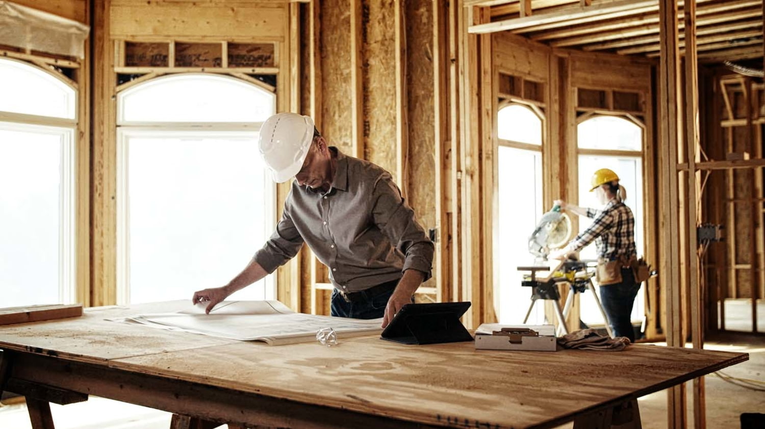 Bauunternehmer begutachtet Pläne auf einer Baustelle