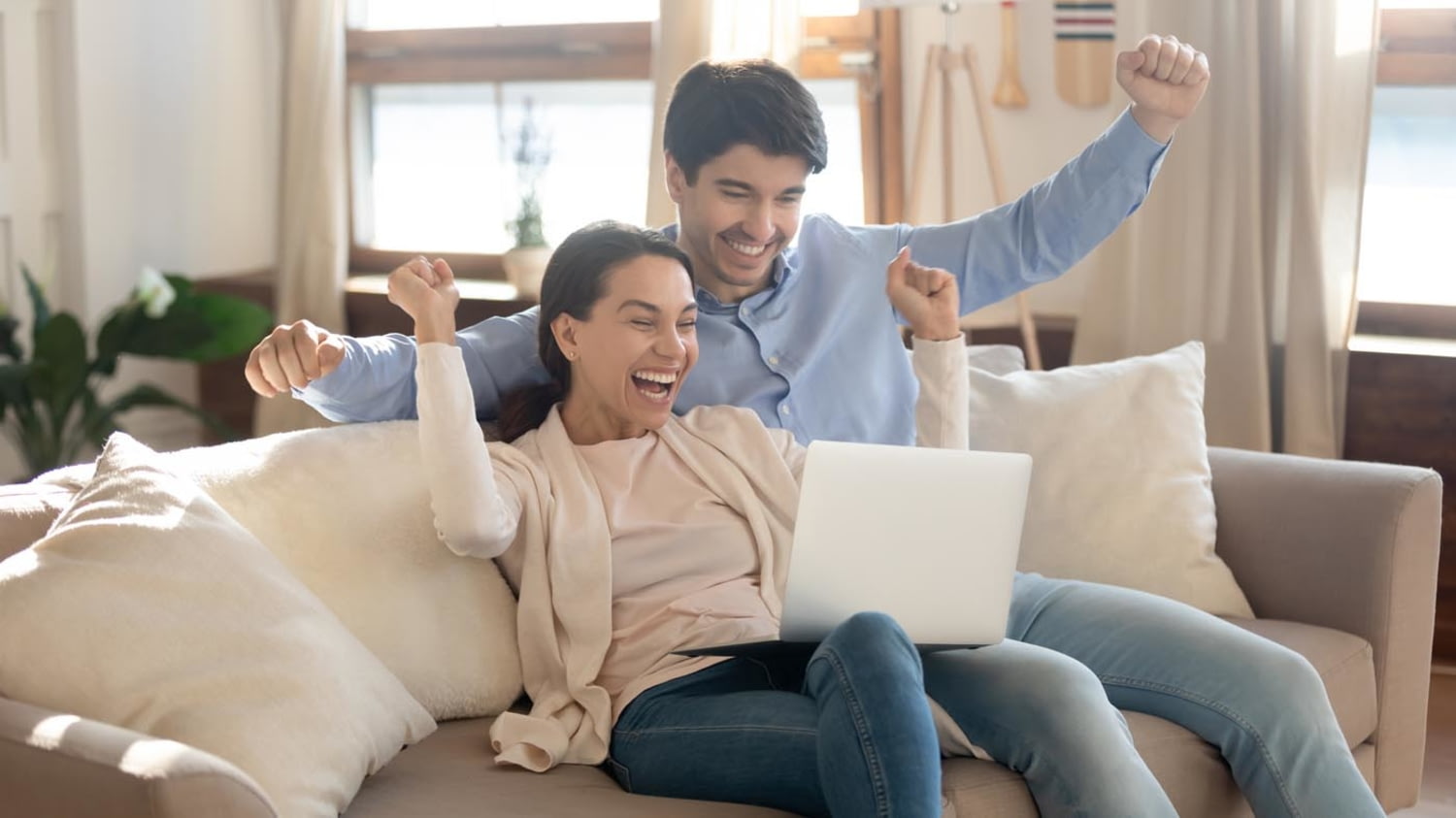 Ein junges Paar freut sich überschwänglich beim Blick auf die gute Entwicklung seines Crowdinvestments