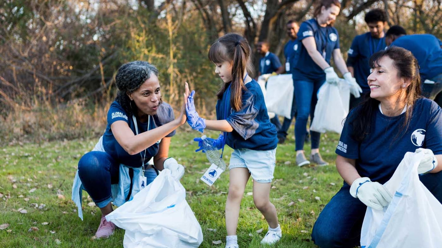 Menschen in blauen T-Shirts sammeln Müll auf