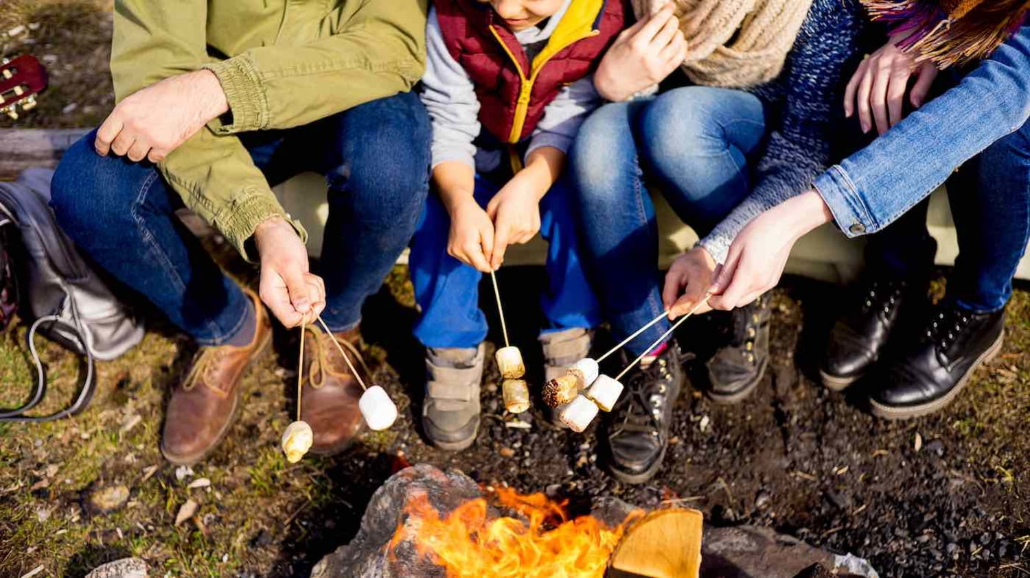 Eine Familie sitzt um ein Lagerfeuer und grillt Marshmallows