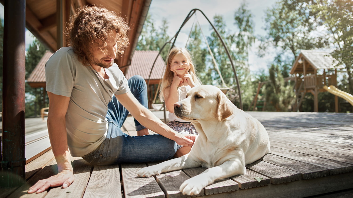 Vater und Tochter sitzen mit Hund auf einer Veranda