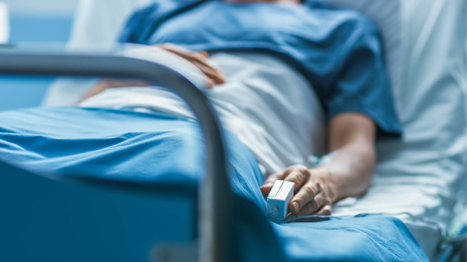 Patient im Krankenhausbett mit Herzfrequenzsensor am Finger