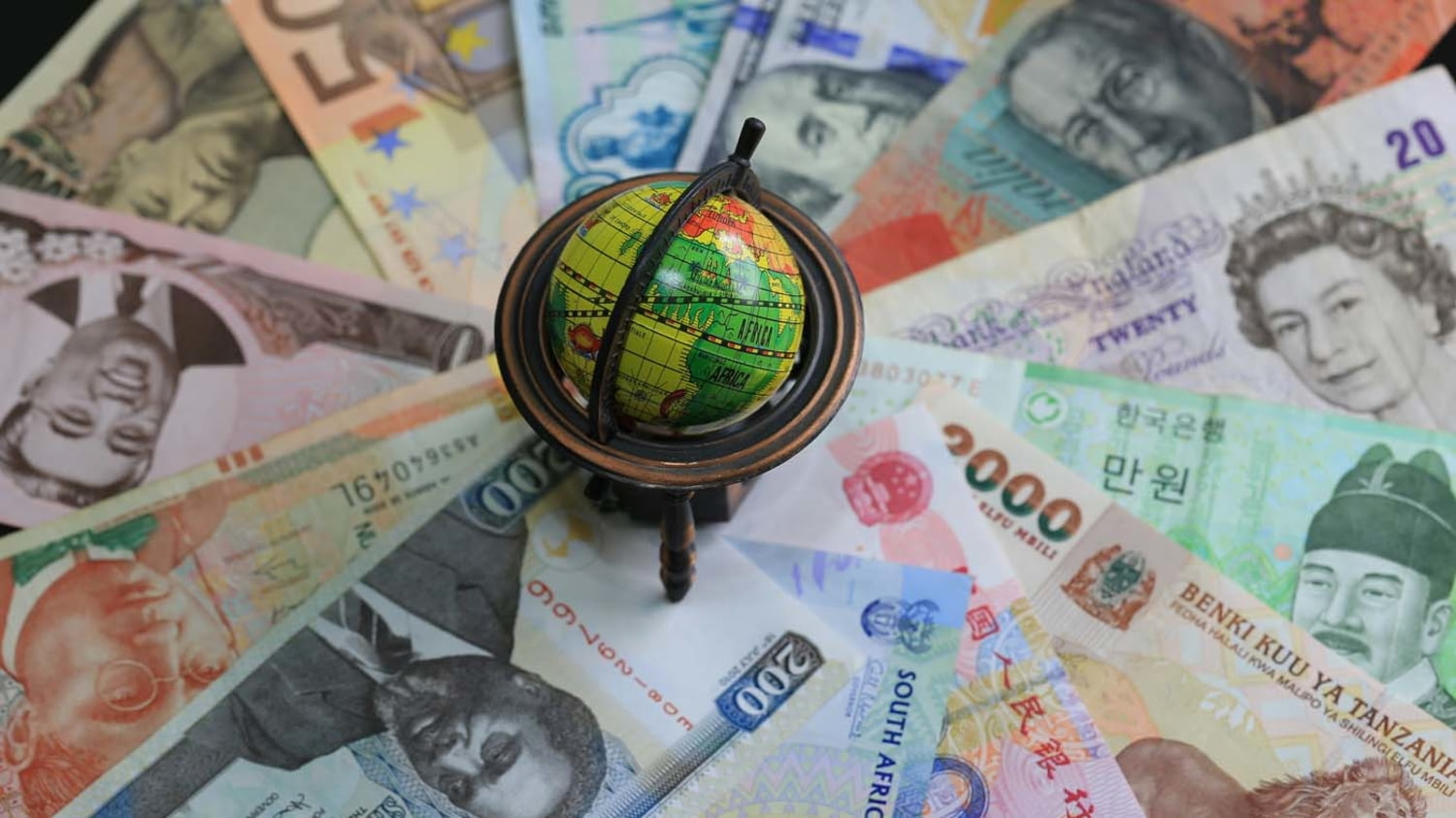 Kleiner Globus auf Geldscheinen unterschiedlicher Währung