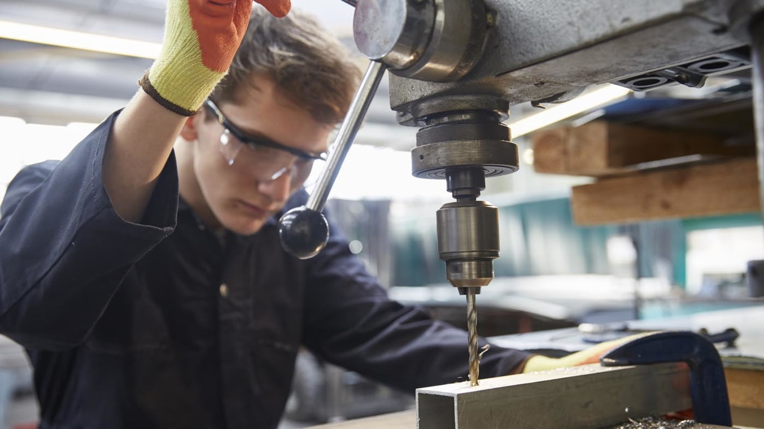 Ein junger Auszubildender fräst ein Loch ein Metallkantrohr