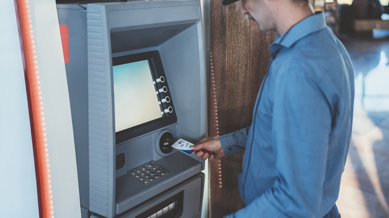 Mann führt eine Karte in einen Bankautomaten ein