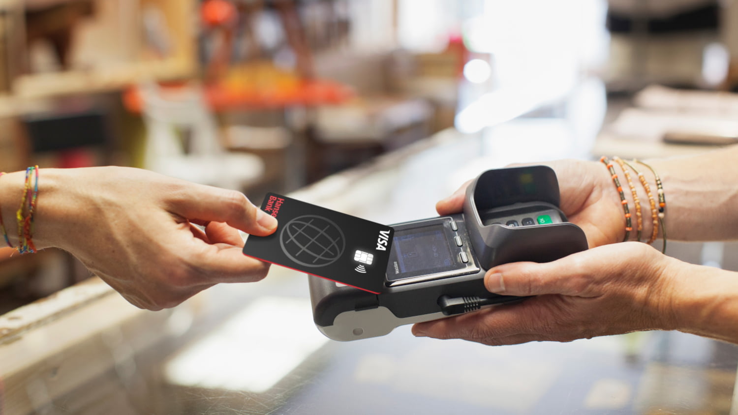 Hand reicht Kreditkarte an ein Bezahlterminal