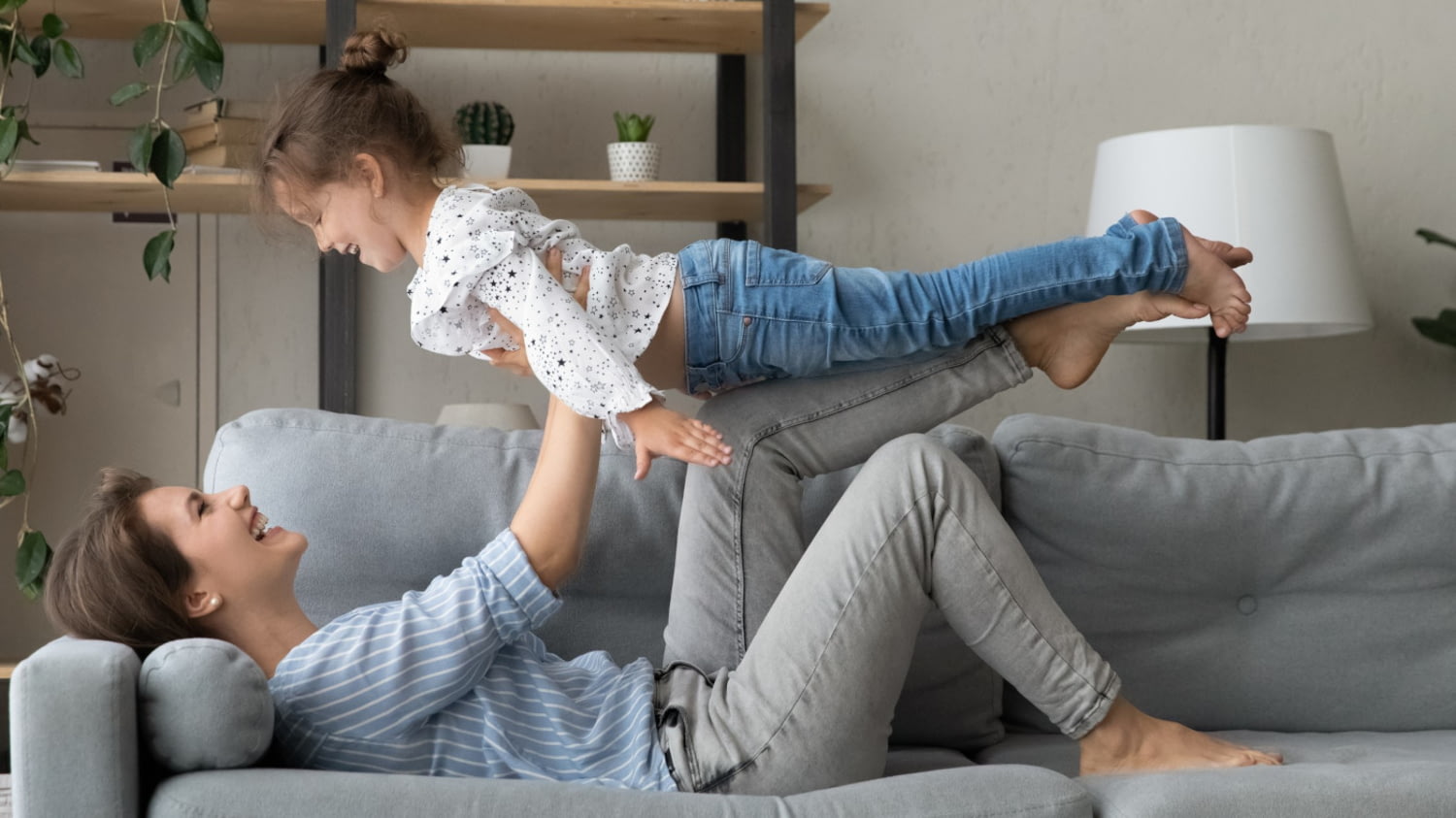 Eine glückliche Mutter hebt ihre Tochter in die Luft