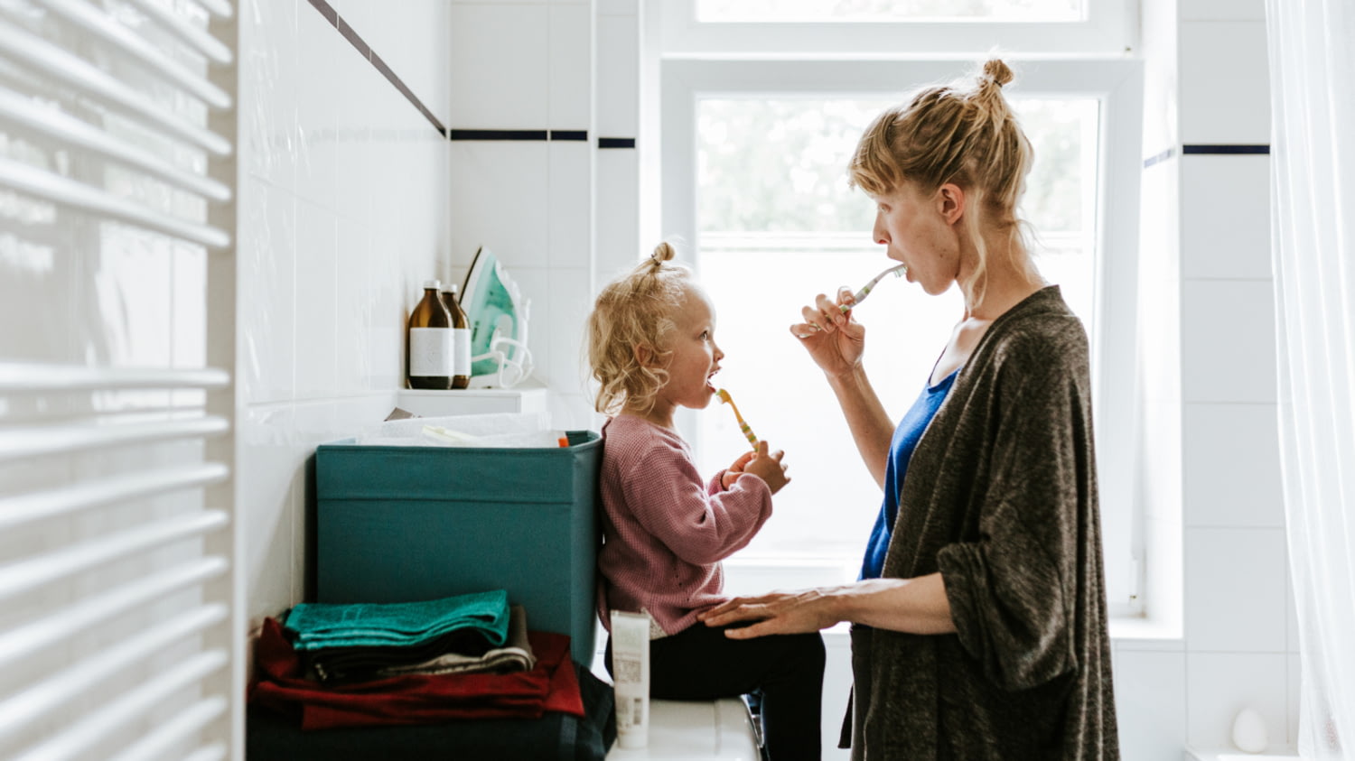 Eine Mutter putzt mit ihrer Tochter im Bad die Zähne