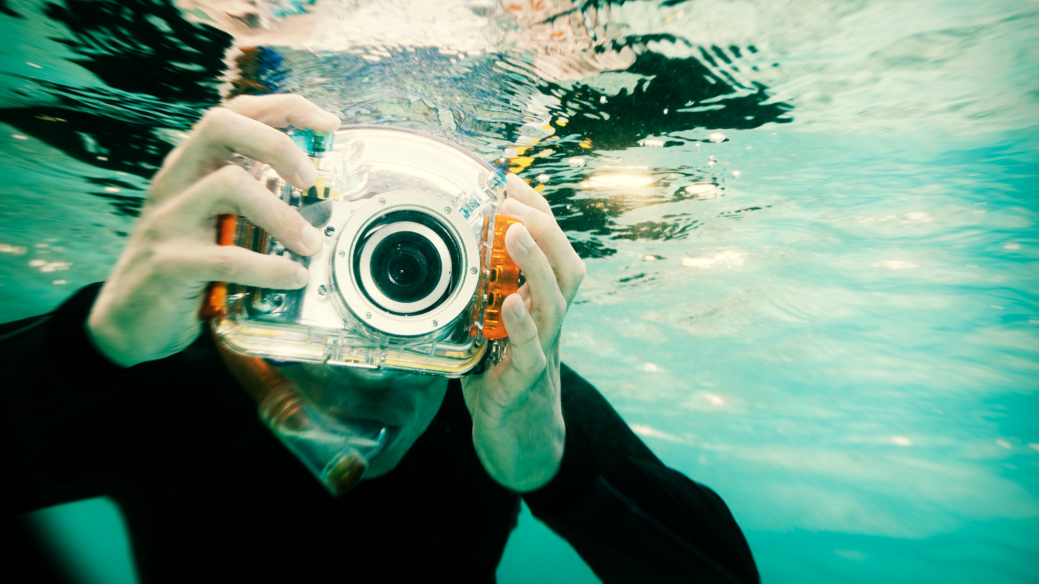 Ein schnorchelnder Mann h&auml;lt eine Unterwasserkamera