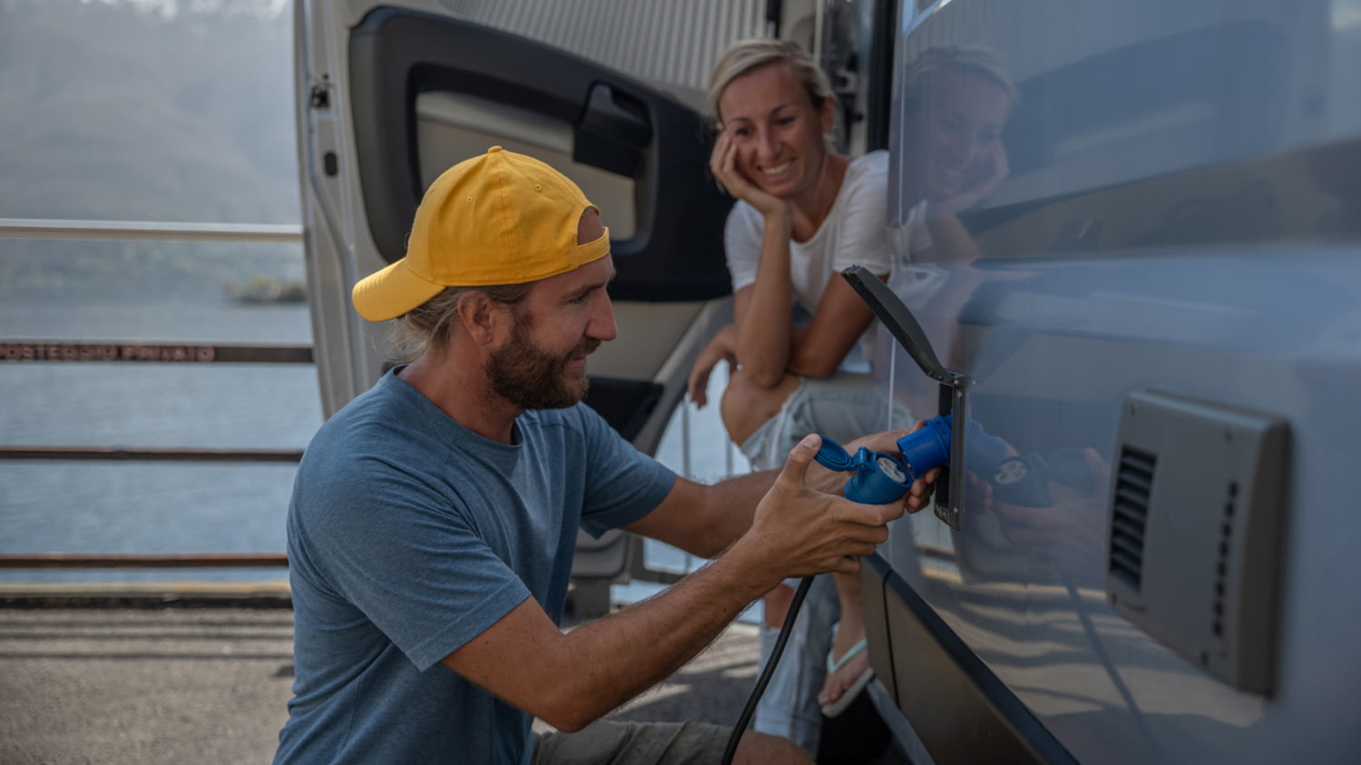 Ein Mann betankt ein elektrisches Wohnmobil mit Strom.