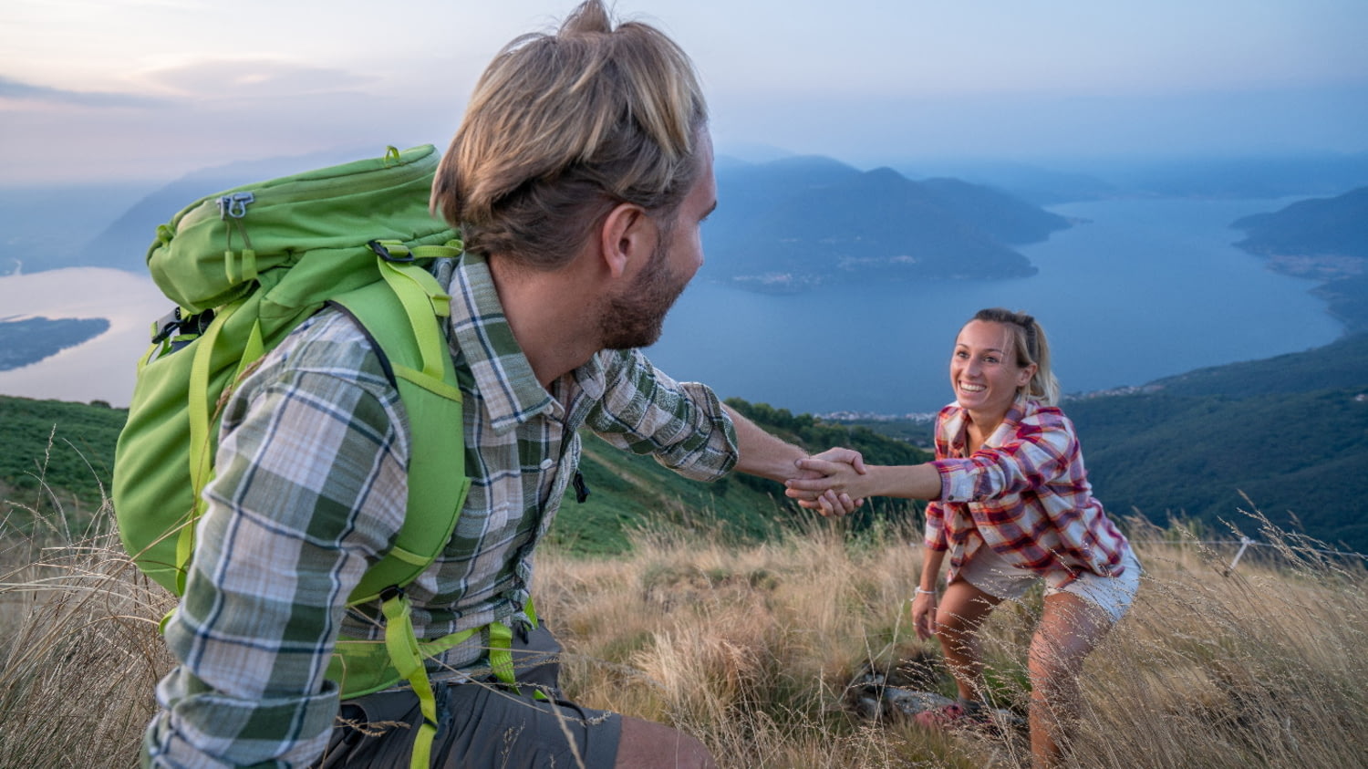 Wanderer reicht mitwandernder Frau eine helfende Hand