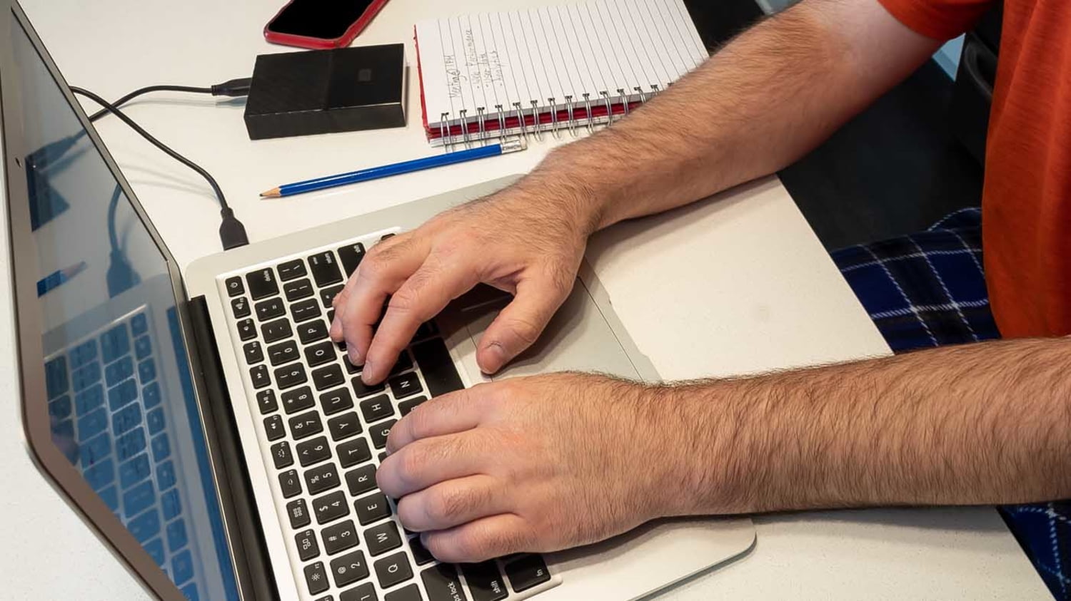 Mann sitzt vorm Laptop und tippt etwas in die Tastatur