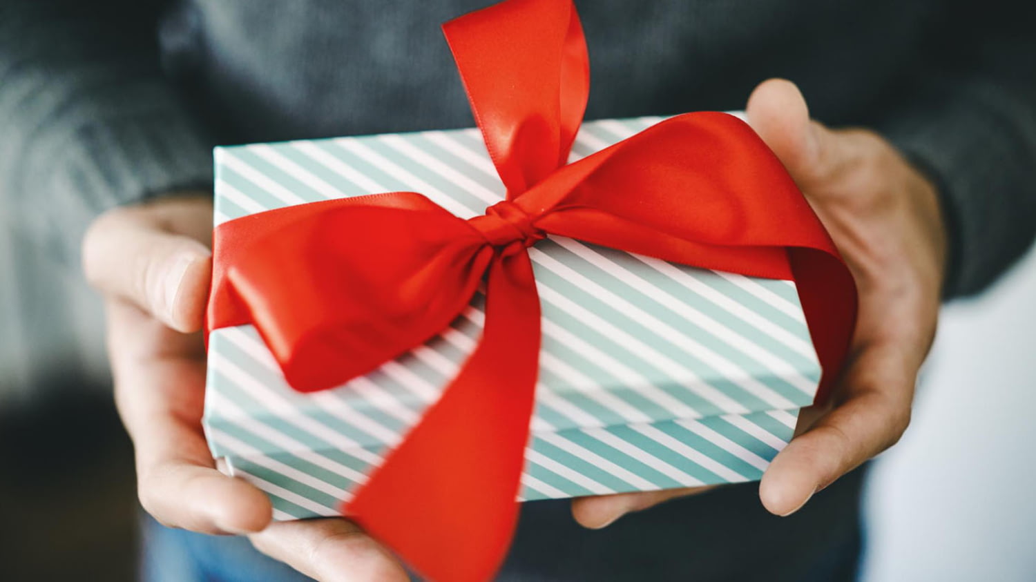 Mann überreicht Geschenkbox mit roter Schleife