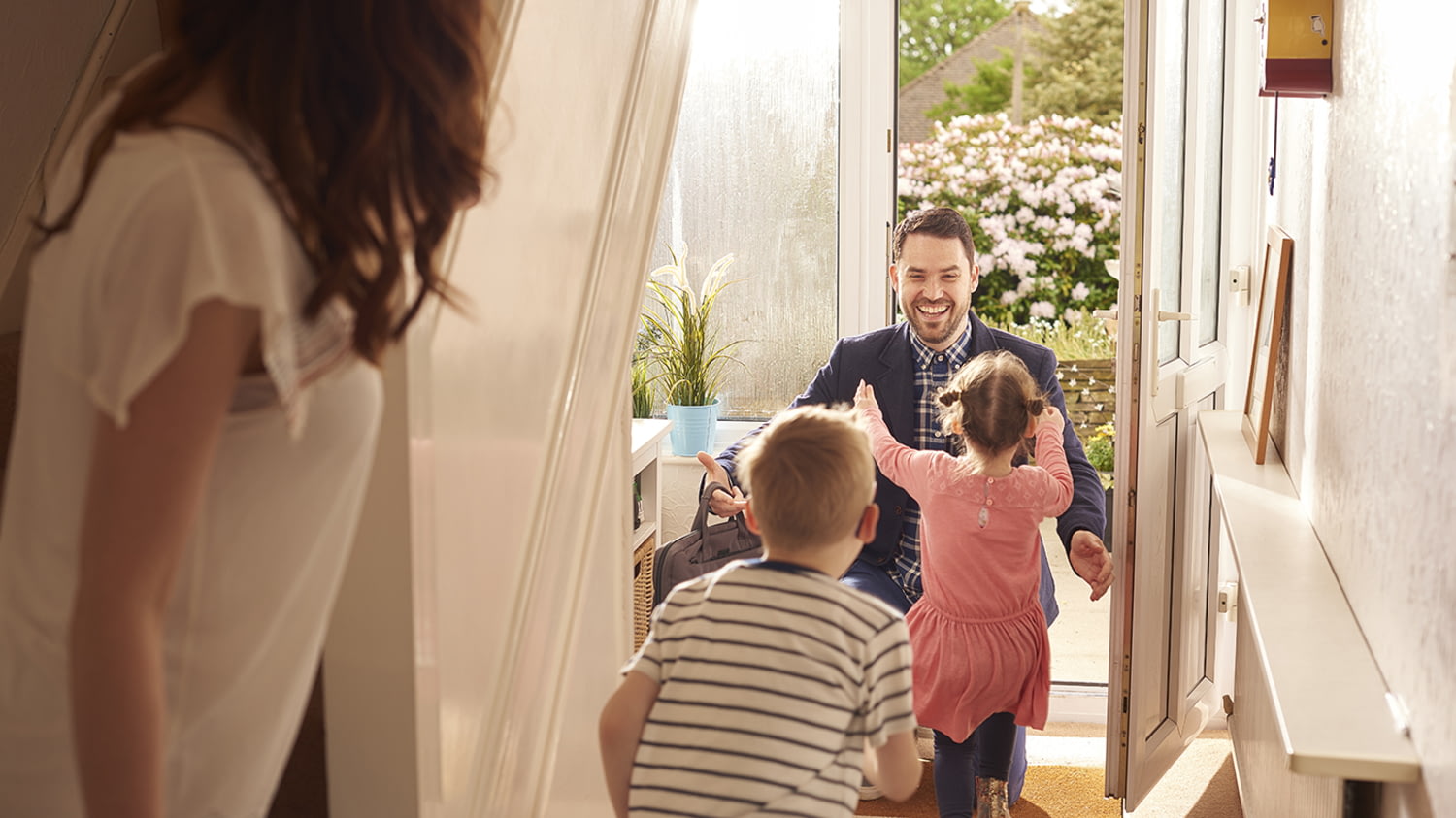 Ein Vater kommt nach Hause und begrüßt seine heranstürmenden Kinder