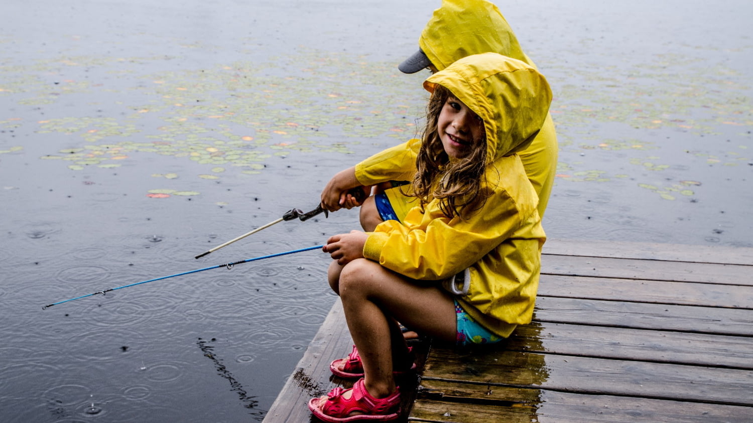 Zwei Kinder angeln bei Regen am See