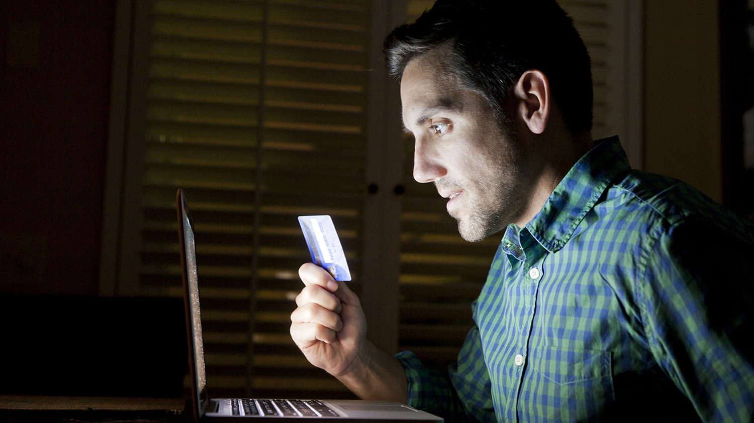 Mann sitzt mit seiner Kreditkarte vor dem Laptop